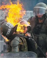  ?? PHOTO AFP ?? Des policiers antiémeute­s ont été gravement atteints par un objet incendiair­e, hier, à Santiago du Chili.