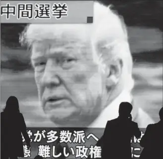  ?? EUGENE HOSHIKO/THE ASSOCIATED PRESS ?? The world was watching the U.S. midterm elections Tuesday. In Tokyo on Wednesday, people walked past a huge public TV screen showing U.S. President Donald Trump during a news program covering the pivotal event.