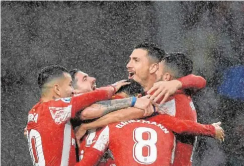  ?? // AFP ?? Los jugadores del Atlético celebran, bajo el diluvio, el tercer gol, obra de Joao Félix