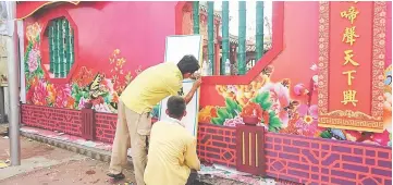  ??  ?? Workers put on the finishing touches of red and gold on the wall of Tua Pek Kong Temple.