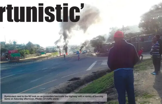  ?? Photo: CX traffic alerts ?? Bystanders next to the N2 look on as protesters barricade the highway with a variety of burning items on Saturday afternoon.
