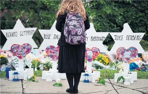  ?? BRENDAN SMIALOWSKI AFP/GETTY IMAGES ?? A woman at a memorial outside the Tree of Life Synagogue in Pittsburgh. Dangerous times in the U.S. and Canada require a strong response, argues Les Scheininge­r.