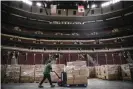  ?? Photograph: AP ?? A worker moves food on to the floor of the United Center in Chicago, which is being used as a storage facility, on 20 March.