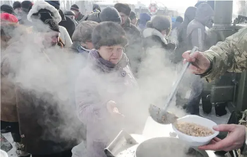  ?? VALEKSEY FILIPPOV / AFP / GETTY IMAGES ?? Rescue workers give food to residents in the Ukrainian town of Avdiivka on Wednesday as government forces and Russia-backed separatist­s battled.