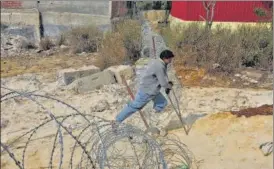 ?? SANCHIT KHANNA/HT ?? A person on crutches crossing concertina wire laid out by police near Ghazipur.
