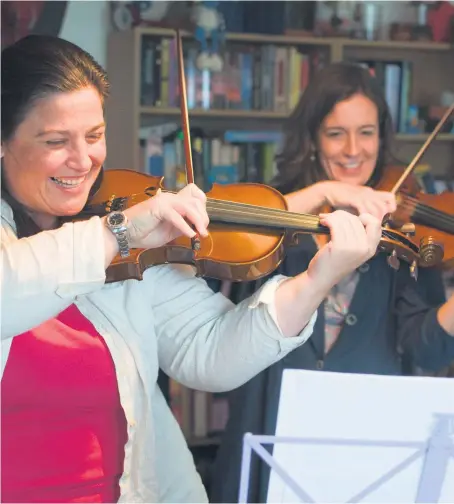  ??  ?? Two violin players of the Scottish Ensemble entertain an audience during one of the group’s residencie­s.