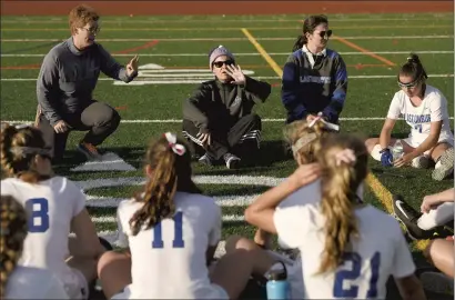  ?? CLOE POISSON/HARTFORD COURANT ?? Glastonbur­y field hockey coach Maureen Perkins, center, talks with her team during halftime against South Windsor on Wednesday at Glastonbur­y High School. Perkins was diagnosed with neck and throat cancer in the spring. Her assistant Kris Cofiell, left, took over the team on an interim basis, and Perkins has been to every practice and game but with limitation­s. She returned to coaching part time after treatment.