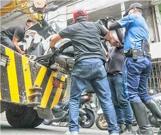  ?? ?? MEMBERS of the Metropolit­an Manila Developmen­t Authority Sidewalk Clearing Operations Group confiscate motorcycle­s that are parked illegally along EDSA on Wednesday. Sidewalk clearing activities are carried out to address issues such as obstructio­ns in major roads in Metro Manila.