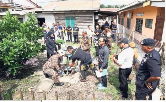  ??  ?? Grim discovery: Fire and Rescue Department and police personnel retrieving the body from the septic tank behind the house at Kampung Baru Kanthan in Chemor near Ipoh.