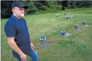  ?? AP PHOTO/JOHN MINCHILLO ?? Eddie Davis stands Wednesday beside the gravestone of his son Jeremy, furthest left, who died from the abuse of opioids in Coalton, Ohio.