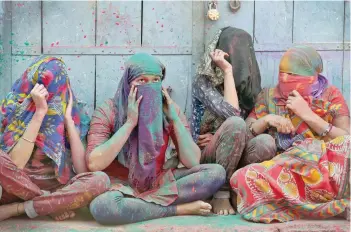  ?? — Reuters ?? Women cover their faces during Holi celebratio­ns in the town of Barsana in Uttar Pradesh on Monday.