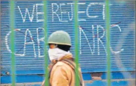  ?? ANI ?? ■
Police personnel walk past a graffiti during a protest against the Citizenshi­p Amendment Act, at Seelampur in New Delhi on Tuesday