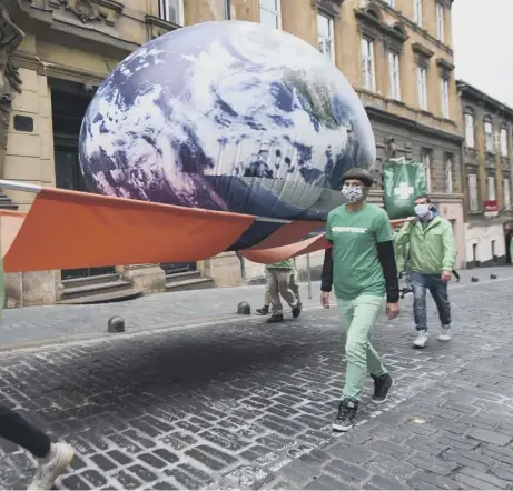  ??  ?? 0 Greenpeace activists carry a giant balloon representi­ng planet Earth.