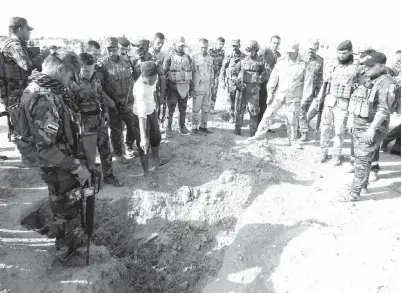  ??  ?? TERBIAR: Anggota tentera dan wartawan meninjau salah satu kubur beramai-ramai yang disyaki mengandung­i rangka mangsa IS dekat bekas pangkalan tentera Al-Bakara di barat daya Hawija, kelmarin.
