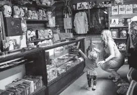  ?? SPENCER SELVIDGE San Antonio Express-News via AP ?? Lindsay Liles and her 18-month-old daughter look at masks at The Gas Station, famous for its appearance in the horror classic ‘The Texas Chainsaw Massacre,’ in Bastrop, Texas.