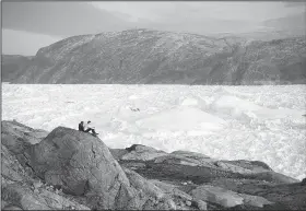  ?? AP file ?? New York University student researcher­s sit Friday on a rock overlookin­g the Helheim glacier in Greenland.