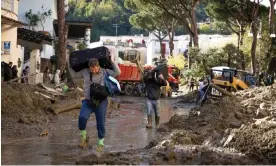  ?? Roberto Salomone/The Guardian ?? Men carry possession­s through a street covered in mud after landslides on Ischia. Photograph: