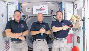  ?? COURTESY OF NASA ?? Astronaut Chris Cassidy, right, rings the opening bell of the Nasdaq Stock Exchange accompanie­d by fellow astronauts Robert L. Behnken, left, and Doug Hurley Tuesday aboard the Internatio­nal Space Station.