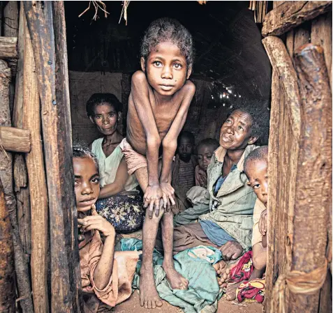  ?? ?? Horariby, a mother of four, looks at her malnourish­ed daughter, surrounded by the rest of her family in drought-hit Marofoty in southern Madagascar