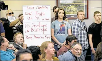  ??  ?? Bob Welch (left), of Bastrop, and Jim Dillon, of Liberty Hill, hold a sign at the special meeting about the
Jade Helm 15 military training exercise at the Bastrop County Commission­ers Court in Bastrop on Monday.