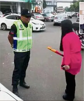  ??  ?? Grace under fire: A woman confrontin­g Norsafuan with a steering lock after he clamped her car that was parked at a space for the handicappe­d. (Inset) Norsafuan received a commendati­on letter for handling the situation in a profession­al manner.