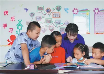  ?? PHOTOS PROVIDED TO CHINA DAILY ?? Peng Jing reads a world atlas with her students in Minning town, Ningxia Hui autonomous region, last year.