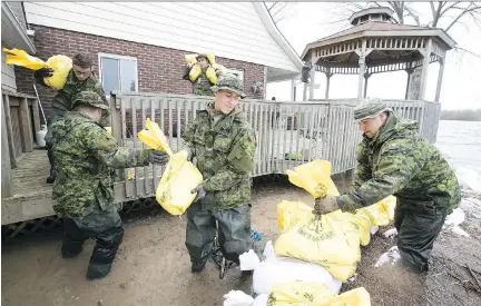  ?? PIERRE OBENDRAUF ?? Canadian military personnel from Valcartier shore up a sandbag wall on De Gaulle St. in Pierrefond­s on Sunday.