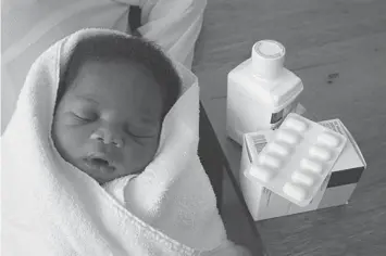  ?? (AFP) ?? A file photo shows five-day old 'Princess' sleeping in her mother's arms next to antiAIDS drug Nevirapine at one of the 18 national test sites, at the T C Newman hospital in Paarl, some 60 kilometers from Cape Town.