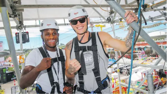  ?? AL CHAREST ?? UFC fighters Hakeem Dawodu, left, and Jordan Mein hit the zipline during their Calgary Stampede visit on Monday. They are promoting a July 28 UFC event at the Saddledome.