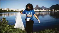  ?? Bruna Prado / Associated Press ?? A volunteer collects garbage from the banks of the Rodrigo de Freitas Lagoon in Rio de Janeiro, Brazil, on June 5, 2021.