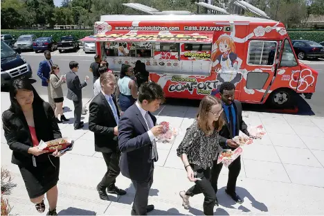  ?? AP Photo/Damian Dovarganes ?? ■ Customers get their lunch June 8 at the Japanese food truck Okamoto Kitchen in Beverly Hills, Calif. Rather than sushi and tempura, they serve meat, fish and sandwiches using traditiona­l Japanese flavors like ponzu.