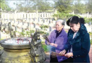  ?? HOANG DINH NAM/AFP ?? Nguyen Thi Hoa (left) and Hoang Thi No, who were members of the Perfume River squad, place incense sticks at an official cemetery where the graves of four comrades who were killed during the 1968 Tet Offensive are located, on the outskirts of Hue, on...