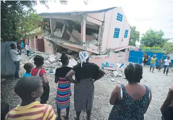  ?? FOTO: AP ?? Pobladores observan una de las estructura­s que resultaron derrumbada­s debido al fuerte movimiento de la tierra que sembró zozobra entre los haitianos.