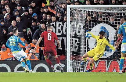  ??  ?? Liverpool goalkeeper Alisson Becker (second right) saves a shot from Napoli striker Arkadiusz Milik (left) during injury time of their UEFA Champions League Group C match at Anfield stadium in Liverpool, northwest England, on Tuesday. The Reds won 1-0 to advance to the last 16. — AFP