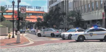  ??  ?? Police cars block a street leading to the Jacksonvil­le Landing area following yesterday’s shooting