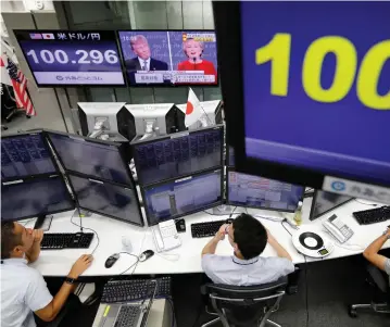 ??  ?? EMPLOYEES OF a foreign exchange trading company watch the first US presidenti­al debate.