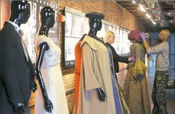  ?? Jessie Wardarski/Post-Gazette photos ?? Darnell McLaurin, right, with FashionAFR­ICANA, sets up a display of costumes by designer Ruth E. Carter before a press conference in March announcing the retrospect­ive fashion exhibition of Ms. Carter’s work at the Heinz History Center.