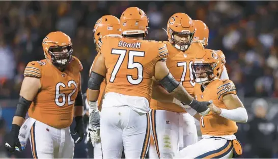  ?? ARMANDO L. SANCHEZ/CHICAGO TRIBUNE ?? Members of the Bears offensive line help quarterbac­k Justin Fields (1) up after he was tackled during the fourth quarter Oct. 13 at Soldier Field.