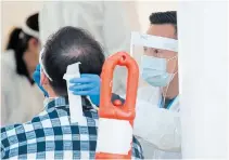  ?? JONATHAN HAYWARD THE CANADIAN PRESS ?? A Fraser Health worker tests a patient at a drive-thru COVID-19 testing facility in Burnaby, B.C., on Monday.