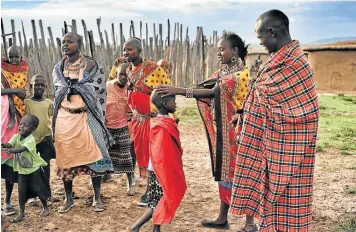  ??  ?? TOUCHING MOMENT: Maasai guides Christina and Wilson greet a local family