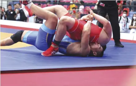  ?? VNS Photo Quý Lượng ?? UNDER PRESSURE: Wrestler Hiếu of Việt Nam (blue) gained a quick win in the men's 130kg Greco-roman on May 17.