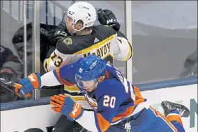  ??  ?? Bruins' Charlie McAvoy and New York Islanders' Kieffer Bellows collide during Monday’s game.