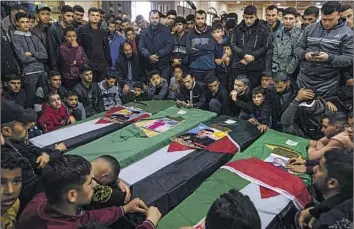  ?? Fatima Shbair Associated Press ?? MOURNERS in Rafah in the Gaza Strip gather last month around the coffins of four Palestinia­ns who died off the Tunisian coast while seeking a better life in Europe. Gaza’s youth unemployme­nt rate is over 60%.