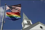  ?? CHARLIE RIEDEL — THE ASSOCIATED PRESS FILE ?? A gay pride rainbow flag flies along with the U.S. flag in front of the Asbury United Methodist Church in Prairie Village, Kan.