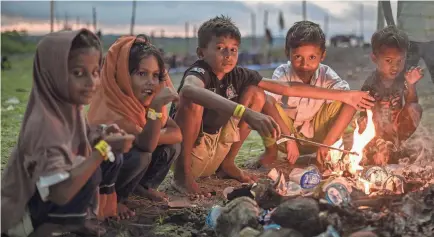  ?? REZA SAIFULLAH/AP ?? Children sit around a fire at their refugee camp near a beach in Aceh province, Indonesia, on Dec. 15. Since November, more than 1,500 Rohingya refugees fleeing Bangladesh by boat have landed in this Indonesian area.