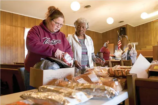  ?? Staff photo by Hunt Mercier ?? A woman picks up food to put into a box while volunteer Christine Williamson helps her picks out the food she wants on Nov. 20 at St. Matthew Baptist Church in Foreman, Ark.