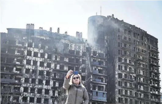  ?? BIEL ALIÑO / EFE ?? Una mujer se toma una fotografía ante el edificio incendiado en Valencia.