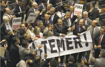  ?? Eraldo Peres / Associated Press ?? Opposition legislator­s carry a banner that reads “Temer Out!” during a key vote on whether to suspend President Michel Temer and put him on trial over an alleged bribery scheme.