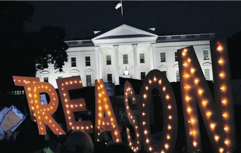  ?? ALEX WONG / GETTY IMAGES ?? Activists holding a candleligh­t vigil to “confront corruption and demand solutions to fix our democracy” displayed a sign spelling out the word “treason” in front of the White House on Wednesday.