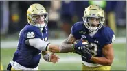  ?? MATT CASHORE — POOL PHOTO VIA AP ?? Notre Dame quarterbac­k Ian Book (12) hands off to running back Kyren Williams (23) during the third quarter of Saturday’s game against Syracuse in South Bend, Ind.